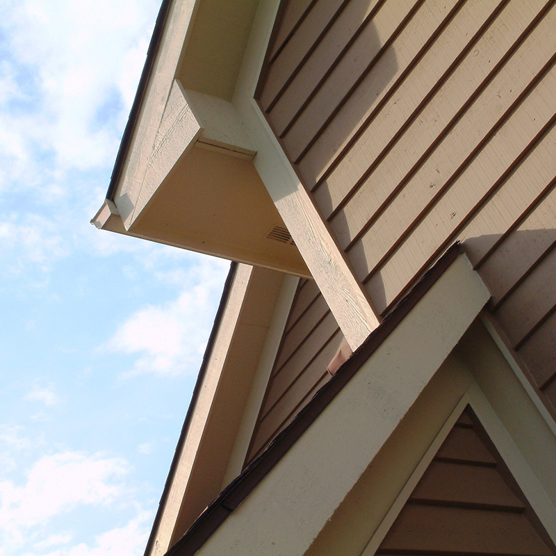House roof elements with cedar wood siding, blue sky and clouds.